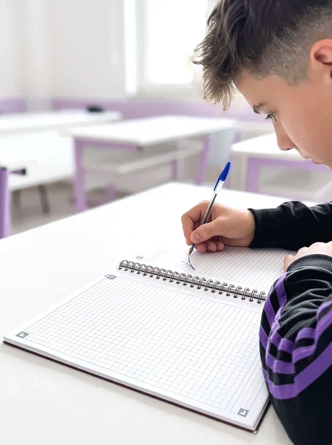 chico escribiendo en cuaderno oxford con cuadros de 5 mm | cuadernos escolares